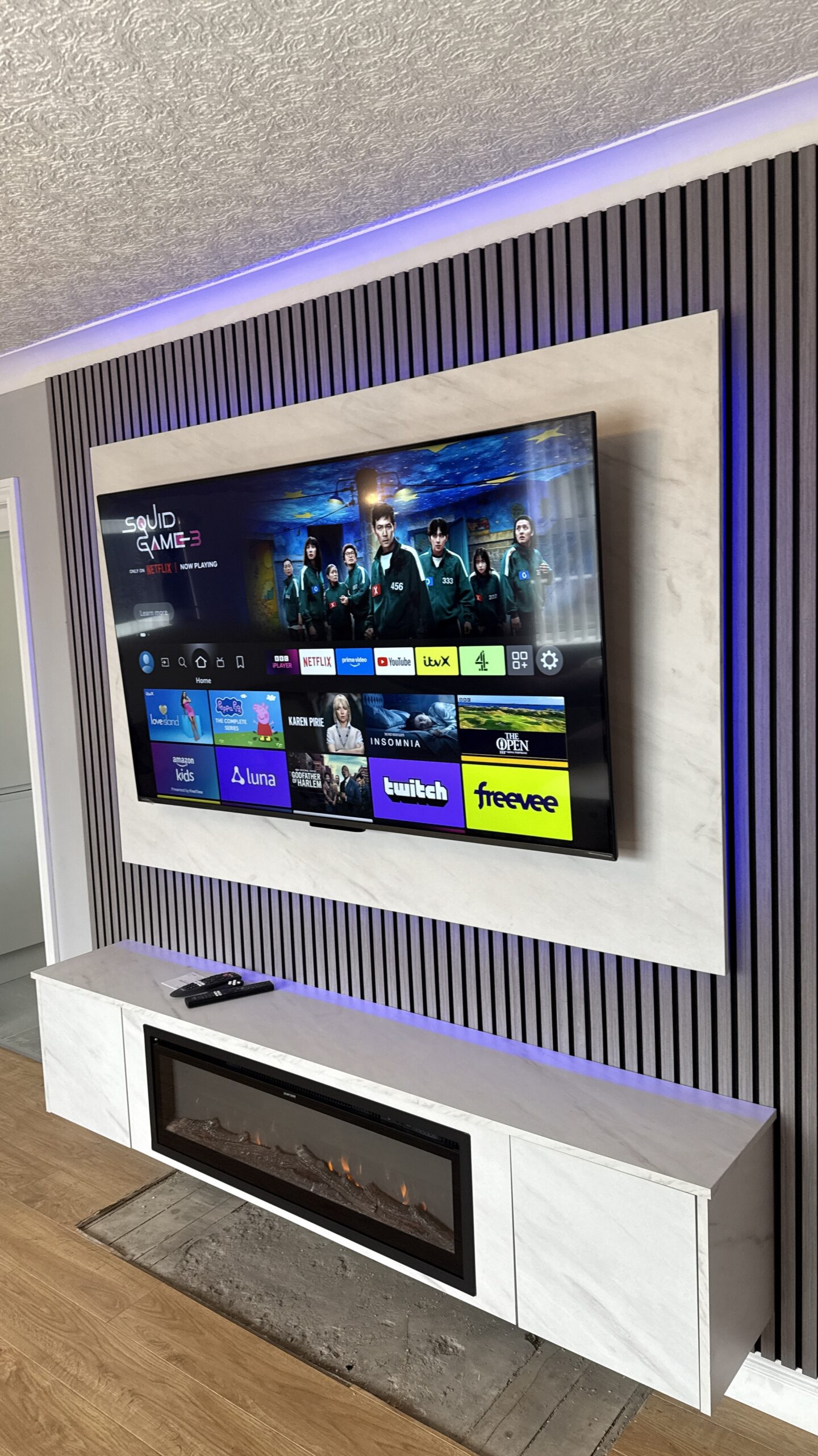 Amazing Feature Wall with Ash Grey Acoustic Slat Panels, Floating Unit with inset Electric Fire and TV Backboard in White Levanto Marble with LED backlights